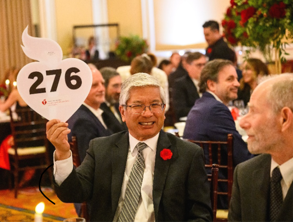 Seated man holding up bidder paddle 276.